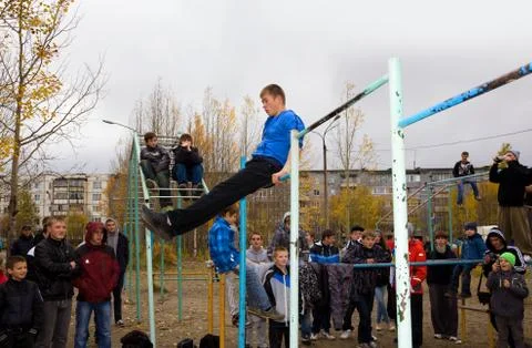 Young guys do exercises on the horizontal bar Stock Photos
