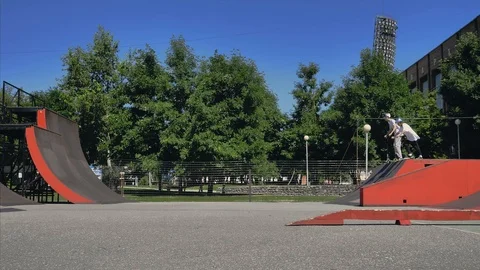 Young guys jumping and doing tricks on a scooter in a skatepark Video stock 94142555