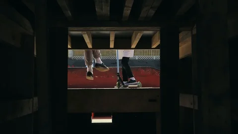 Young guys jumping and doing tricks on a scooter in a skatepark Video stock 94142756