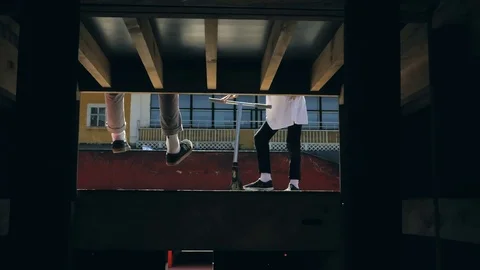 Young guys jumping and doing tricks on a scooter in a skatepark Video stock 94142789