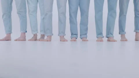 Young guys models, only legs dressed in jeans pass by me on a white background Stock Footage 152790540
