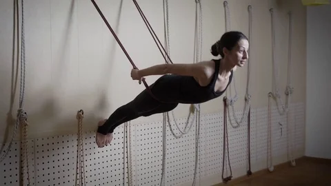 Young gymnast woman is training using ropes fixed on a wall in a sports hall Stock Footage 84005096