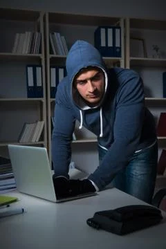 Young hacker hacking into computer at night Stock Photos