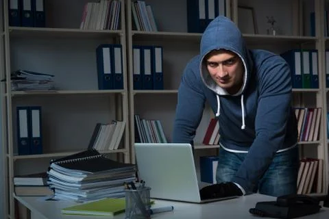 Young hacker hacking into computer at night Stock Photos