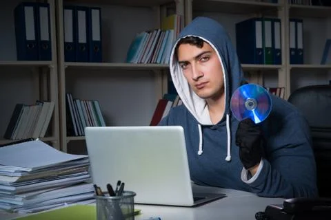 Young hacker hacking into computer at night Stock Photos