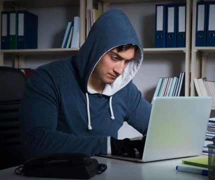 Young hacker hacking into computer at night Stock Photos