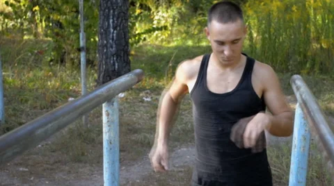 Young half-naked man does exercise on parallel bars in park Stock Footage 67482370