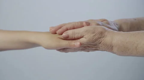 Young hand and the hand of an old woman on a white background close-up Stock Footage