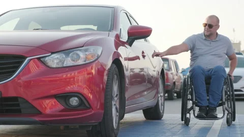 Young handicapped driver getting in red car from wheelchair Stock Footage 160075620
