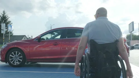 Young handicapped driver getting in red car from wheelchair Stock Footage 160076621