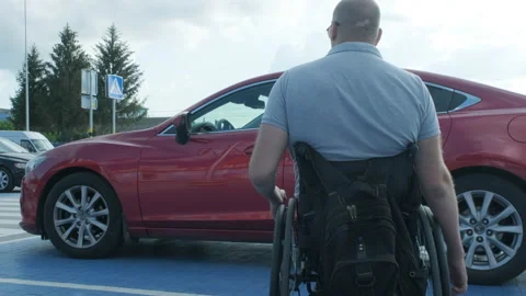 Young handicapped driver getting in red car from wheelchair Stock Footage 160455982
