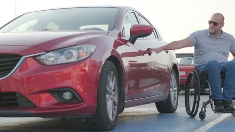Young handicapped driver getting in red car from wheelchair Stock Footage 160460750