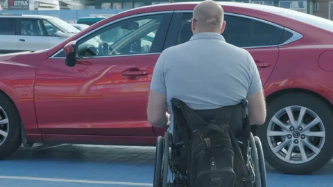 Young handicapped driver getting in red car from wheelchair Stock Footage 160462490