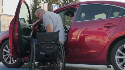 Young handicapped driver getting in red car from wheelchair Stock Footage 160652168