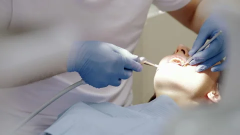 Young hands of the dentist dressed in blue gloves perform a procedure of the Video stock 147226353