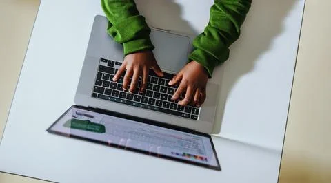 Young hands on a keyboard: Child coding with a laptop in a classroom Stockfoto's