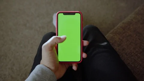 Young hands man sitting on sofa use vertical green screen phone at home living Stock Footage 118472627