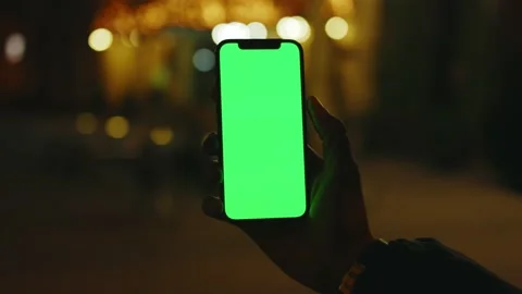 Young hands man use phone with vertical green screen stand at night city street Stock Footage 145899935