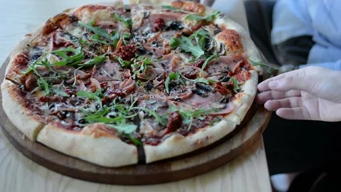 Young hands take a piece of pizza with greens, tomato, pepperoni, enjoying Stock Footage 155353889