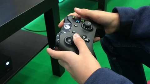 Young hands touching buttons and sticks on Xbox game console Stock Footage 98139745