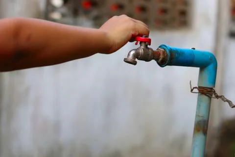 Young hands turning off an old rusty water tap for saving water Stock Photos