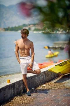 A young handsome and muscular guy is enjoying the view from the quay during.. Stock Photos