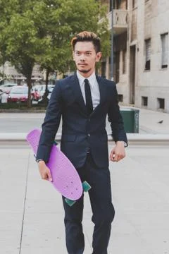 Young handsome Asian model posing with his skateboard Stock Photos
