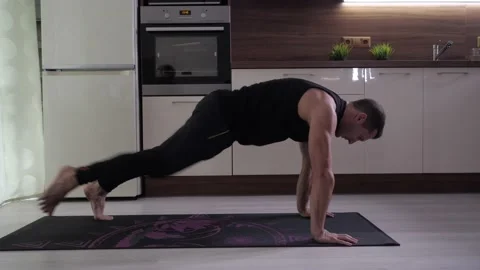 A young handsome athlete performs a difficult exercise in the kitchen Stock Footage 136743106