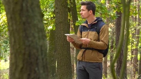A young handsome backpacker examines a map in a forest 스톡 동영상 109333155