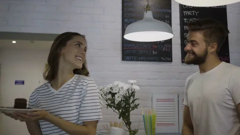 Young handsome bartender giving cake to smiling beautiful female customer Stock Footage 79917546