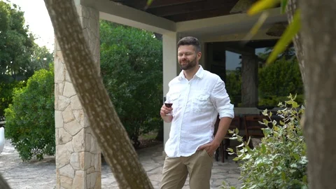 Young handsome bearded man drinks wine in a luxury villa Stock Footage 111665308