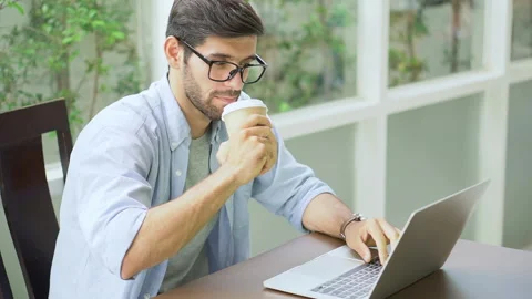 Young handsome bearded man freelancer sitting on desk using laptop computer a Stock Footage 134399388