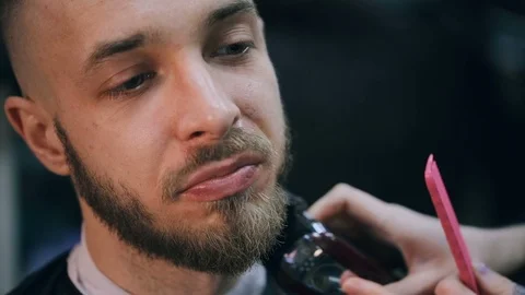 Young handsome bearded man getting a haircut in a modern barber shop. Видео 86477794