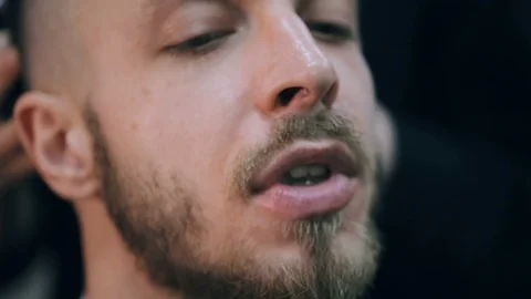 Young handsome bearded man getting a haircut in a modern barber shop. Видео 86477817