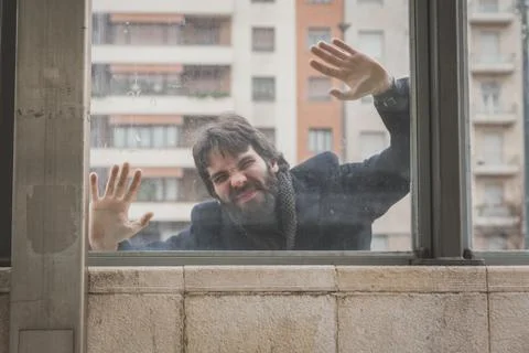 Young handsome bearded man posing behind a glass Stock Photos