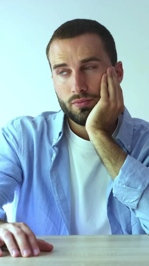 Young handsome bearded man sitting at a desk and looking at camera Stock Footage 345123728