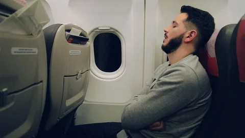 Young handsome bearded man sleeping in airplane seat by the illuminator Video stock 105273067
