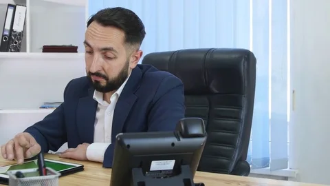 Young handsome bearded man uses touchscreen tablet in the modern startup office Stock Footage 75951714