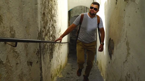 Young handsome bearded man is walking on the dark narrow street Stock Footage 98371589