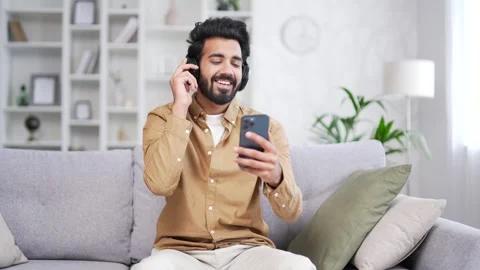 Young handsome bearded man in wireless headphones listening to music while  Stock Footage 252202636