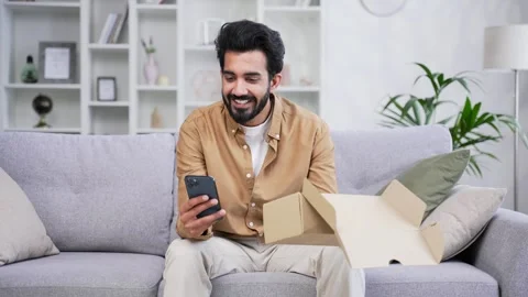 Young handsome bearded man writes a good review on smartphone after receiving  Stock Footage 252204115