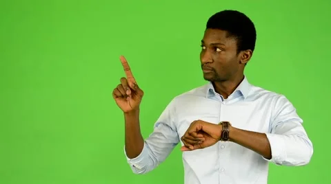 Young handsome black man points to watch - green screen - studio Video stock 45486398