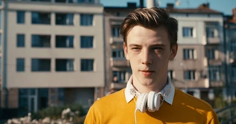 Young handsome blond hispter is walking along the street and putting on his Stock Footage 92008772