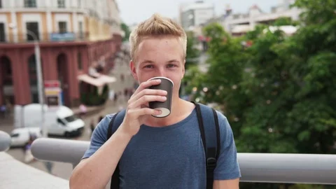 Young handsome blond man drinking coffee and smiling at urban street Stock Footage 92360266