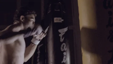 Young handsome boxer working out with boxing bag. Видео 76915774