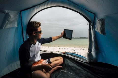 Young handsome boy guy camping directly on the white beach in paradise tropic Fotos de archivo