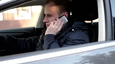 Young, handsome boy sitting inside his car and talking thru the phone Stock Footage 49338778