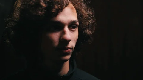 Young handsome boy touching his hair in the dark room, close up 動画素材 99050408