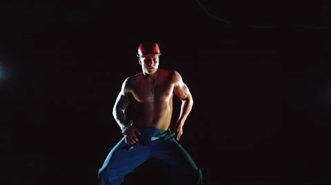 Young handsome builder sexy dancing on dark background Video stock 64022546