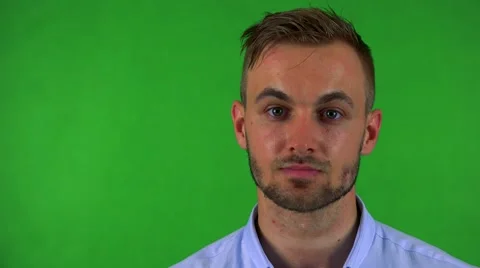 Young handsome business man looks to camera with serious face - green screen Stock Footage